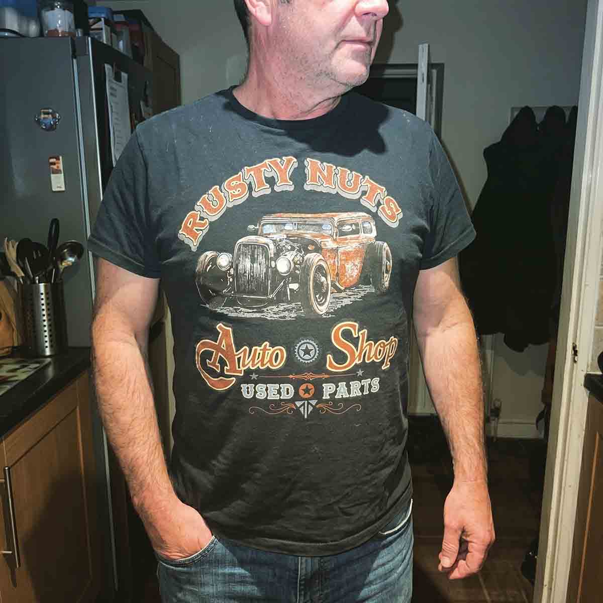 Direct-flash kitchen candid of a man wearing a vintage hot-rod tee